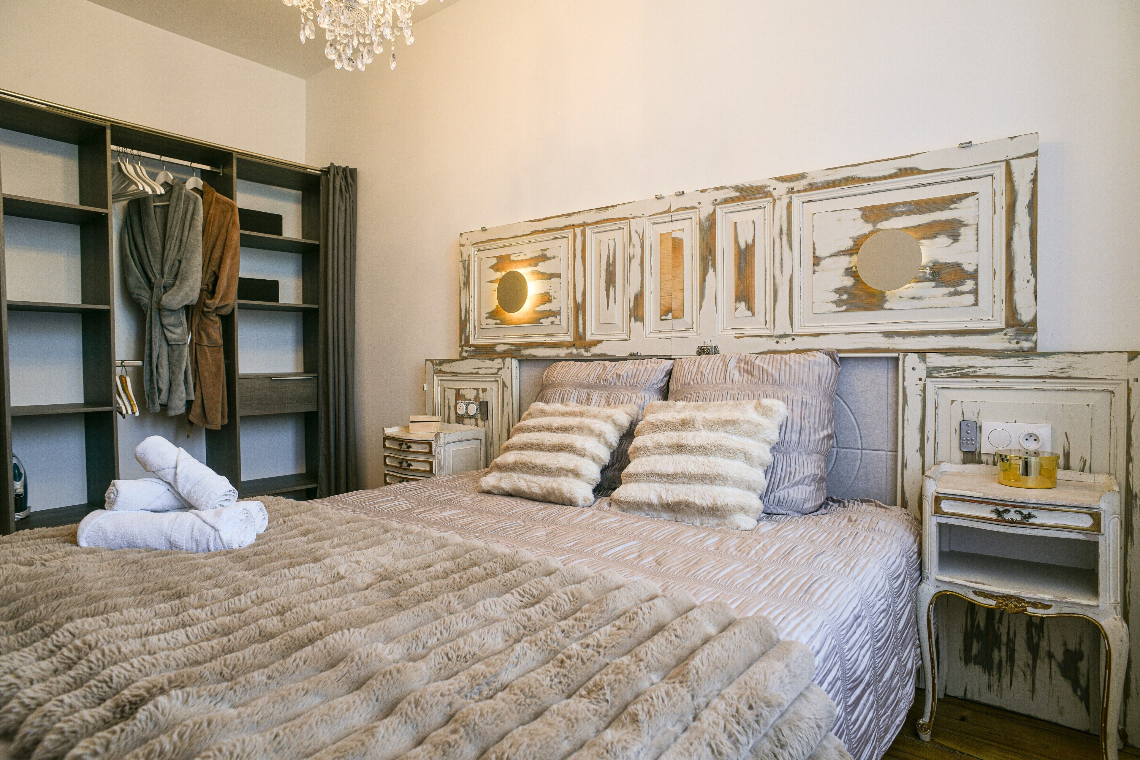 Un dormitorio con una cama grande, un armario, un tocador y una estantería en la pared.