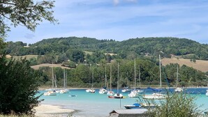 Marina costera con barcos amarrados, rodeada de vegetación y colinas.