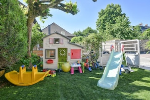 A children's play area with a slide, a small house, and a yellow boat.