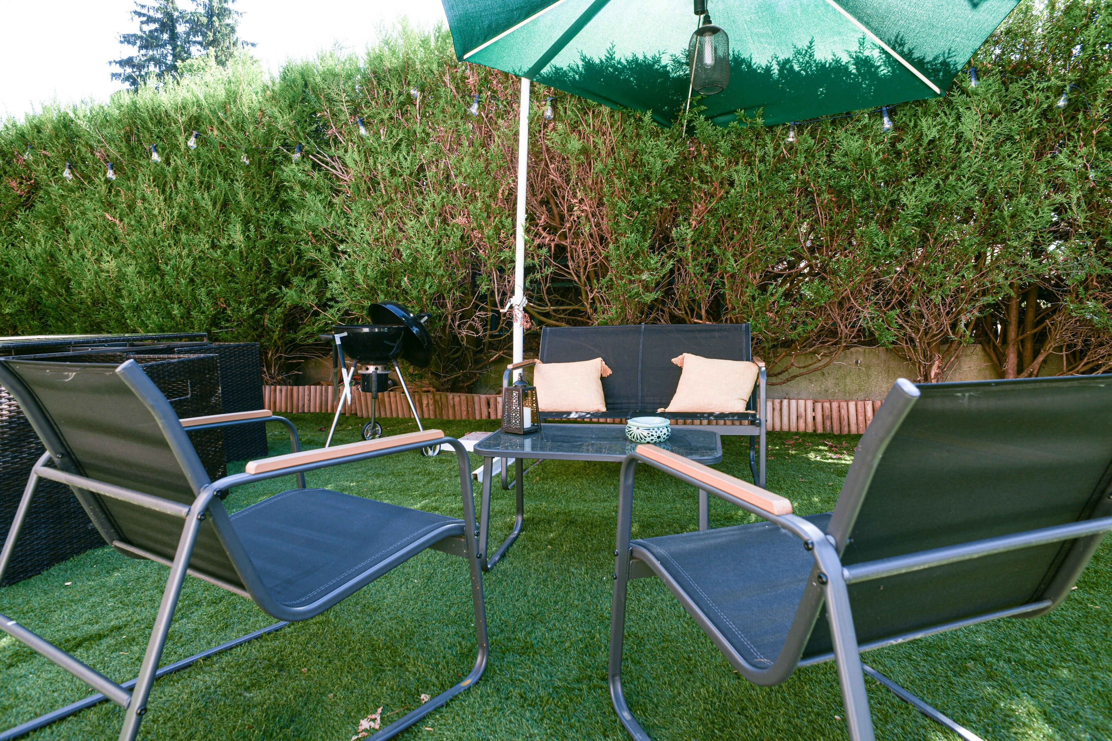 Eine Terrasse im Freien mit Tisch, Stühlen und Sonnenschirm.