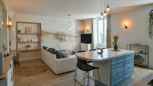 Una cocina moderna con una isla central, taburetes de bar y un rincón de comedor con sofá.