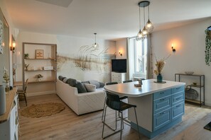 Eine moderne Küche mit Kochinsel, Barhocker und einem Essbereich mit einer Couch.