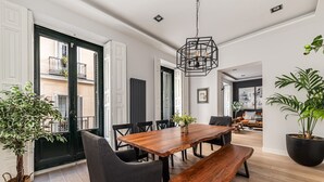 A dining area with a wooden table, black chairs, and a hanging light fixture. - Waou Justice V - Short Term Rental (Madrid)