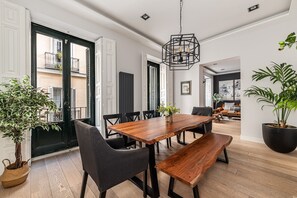 A dining area with a wooden table, black chairs, and a hanging light fixture. - Waou Justice V - Short Term Rental (Madrid)