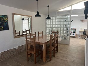 A dining area with a wooden table and chairs, a large mirror, and a window with frosted glass panels.