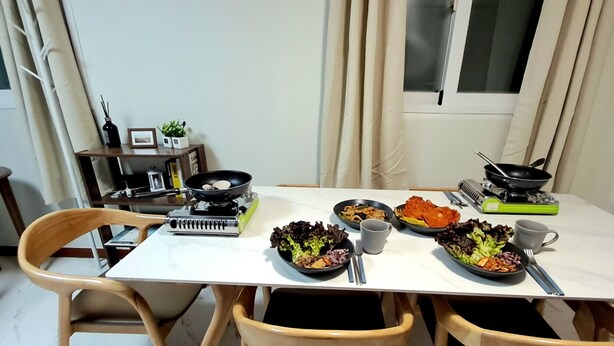 A dining table with four chairs, a portable stove, and various dishes. - Dodahm Guesthouse (Incheon)