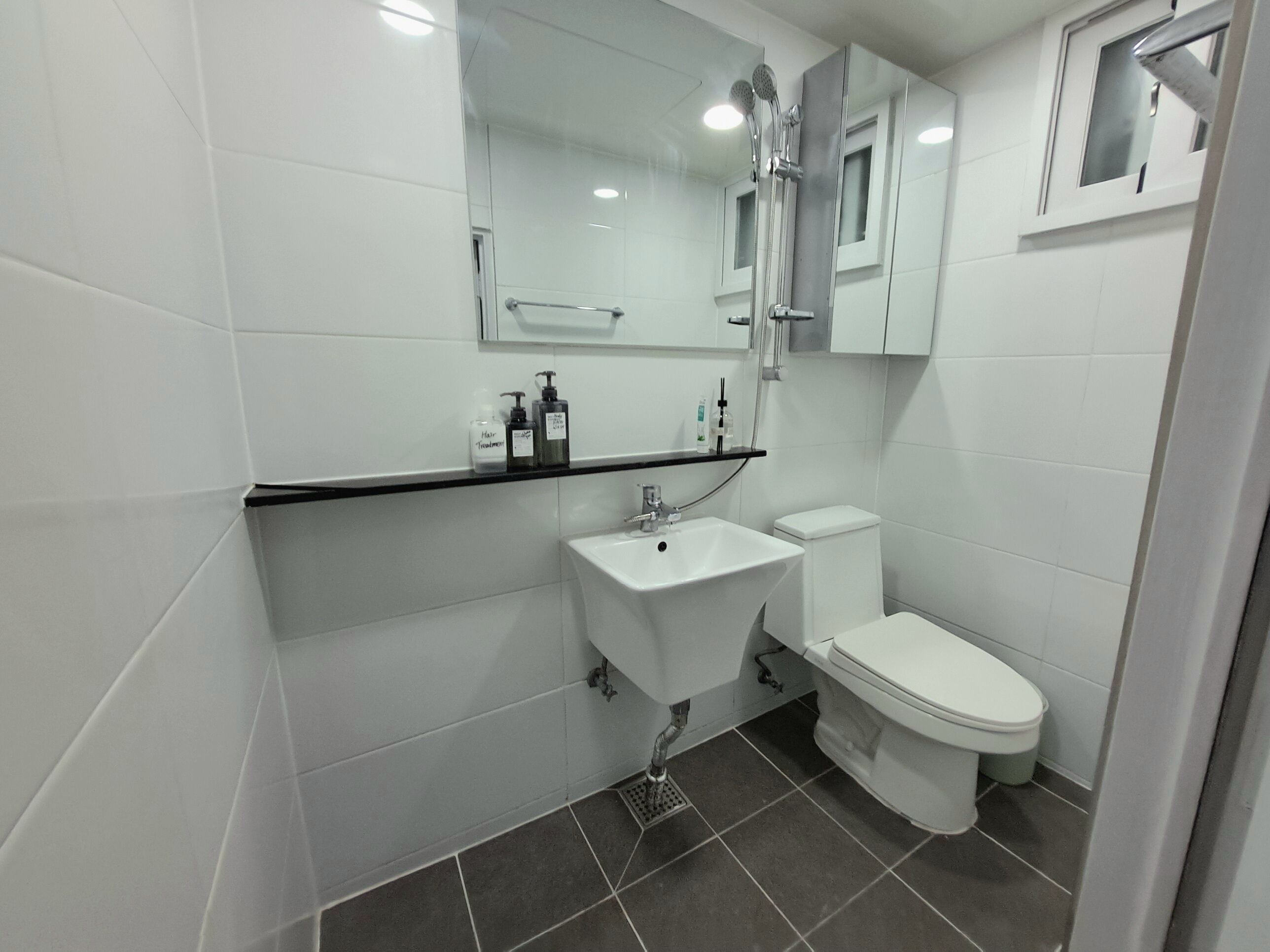 A modern bathroom with a white sink, toilet, and a mirror above the sink.