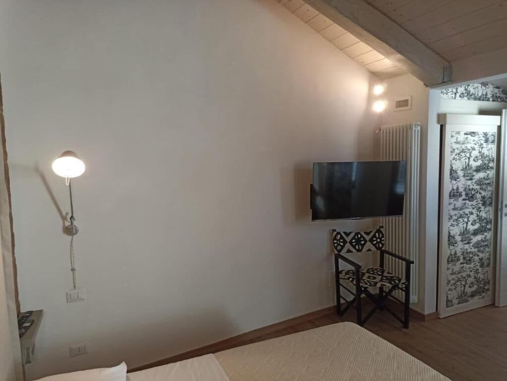 Une chambre avec un lit, un téléviseur à écran plat fixé sur un support, un radiateur et une porte à motifs.