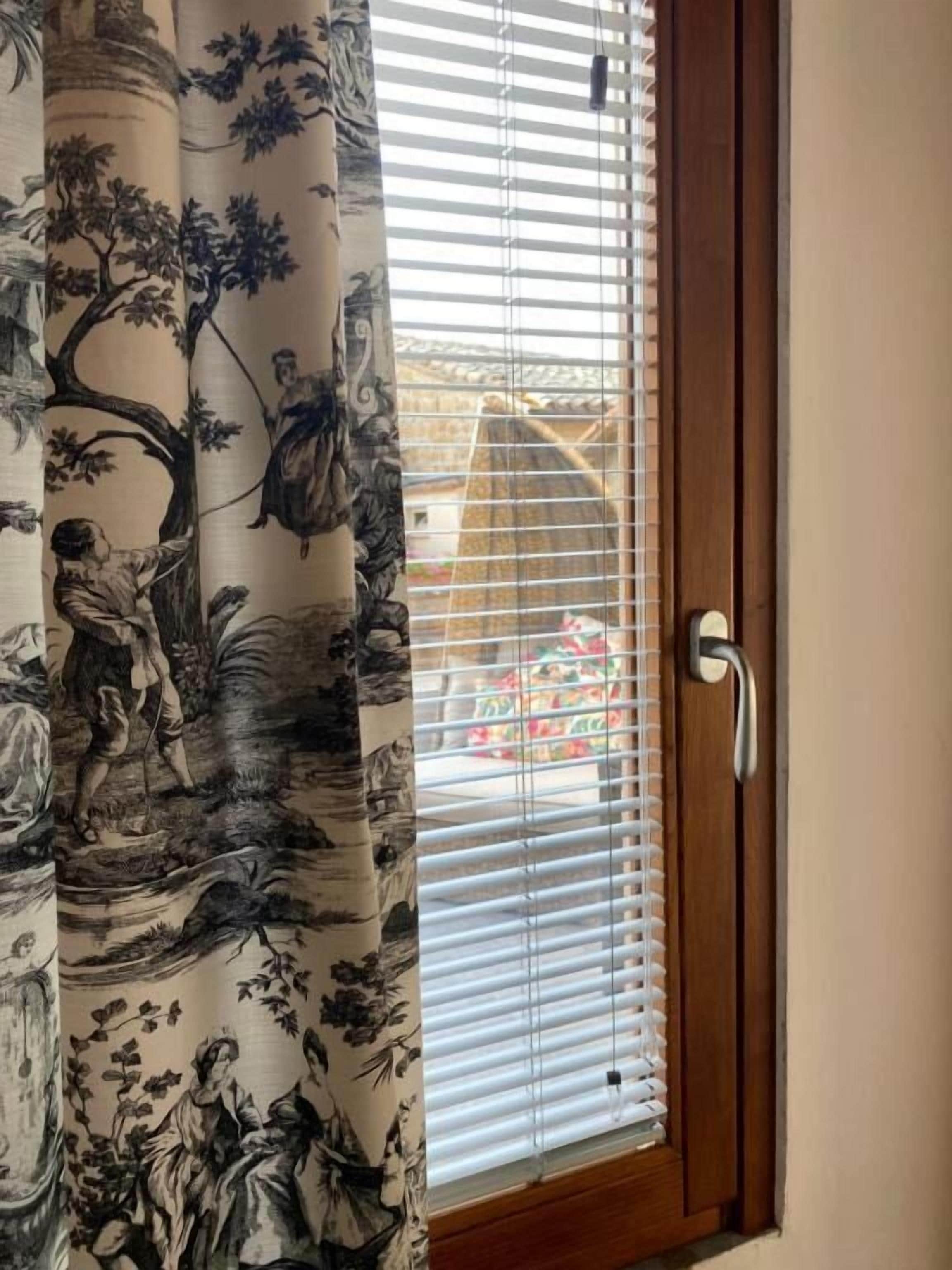 Una habitación con puerta de madera y ventana con persianas.