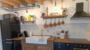 Uma cozinha com geladeira preta, pia, armários de madeira e fogão.