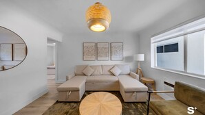A modern living room with a sectional sofa, a round coffee table, and a hanging light fixture. - Chic 1-BD Apt in Miami Gym-Free Parking (North Miami)