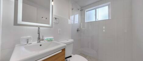 A modern bathroom with a white sink, mirror, and toilet.