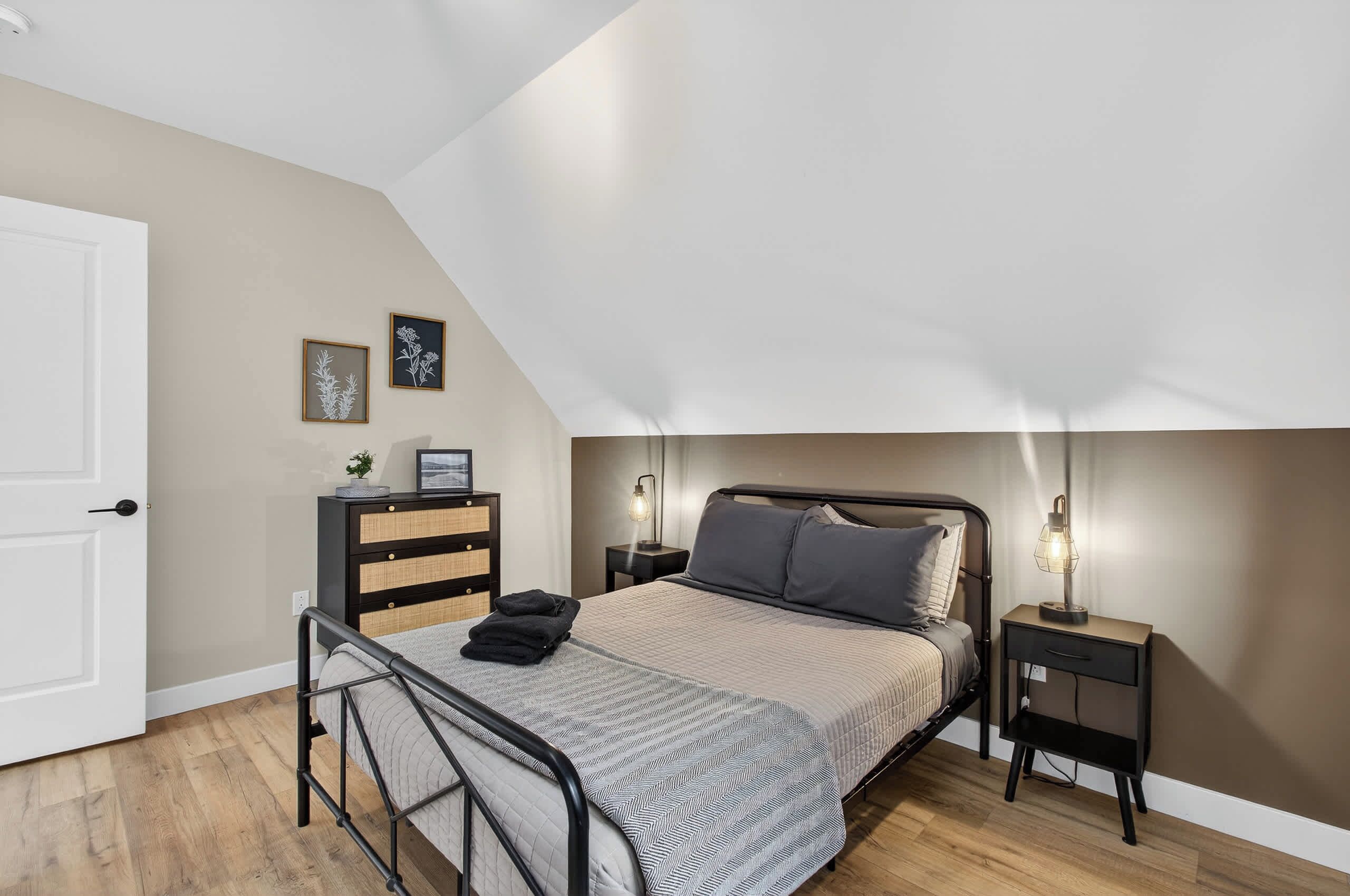 A bedroom with a bed, bedside tables, a dresser, and a door.