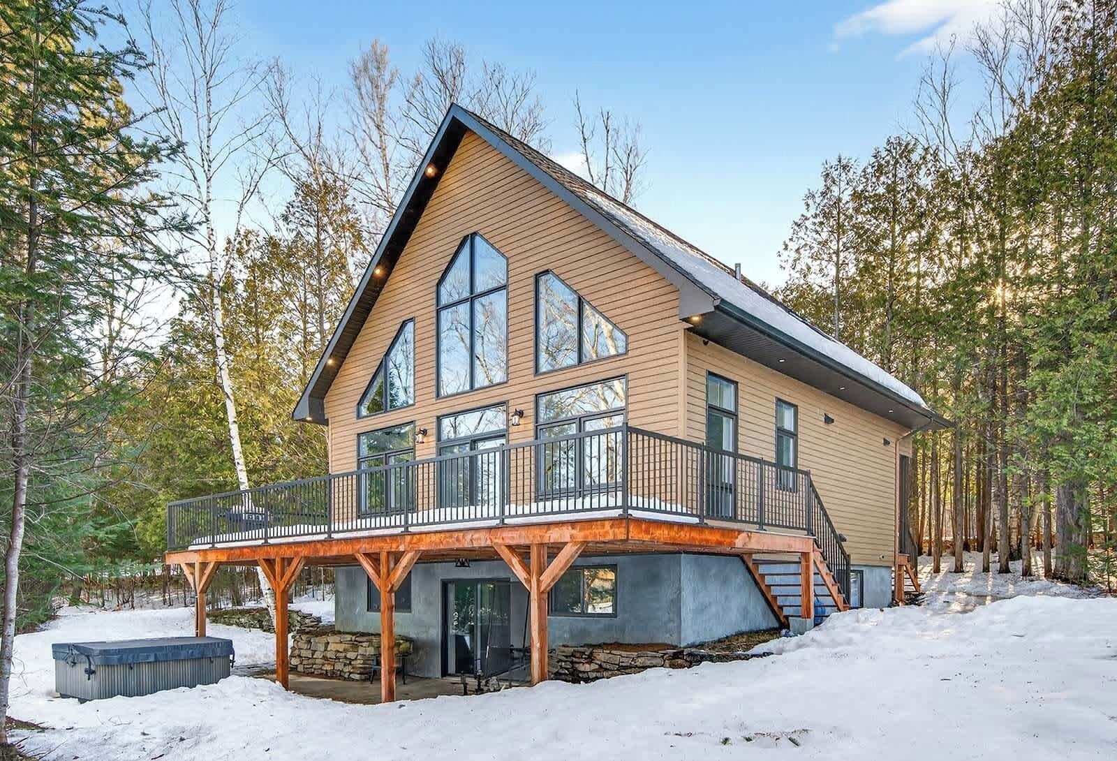 Une grande cabane moderne en rondins de bois, dotée d’un balcon bien visible et d’une fondation en pierre.