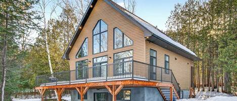 Une grande cabane moderne en rondins de bois, dotée d’un balcon bien visible et d’une fondation en pierre.