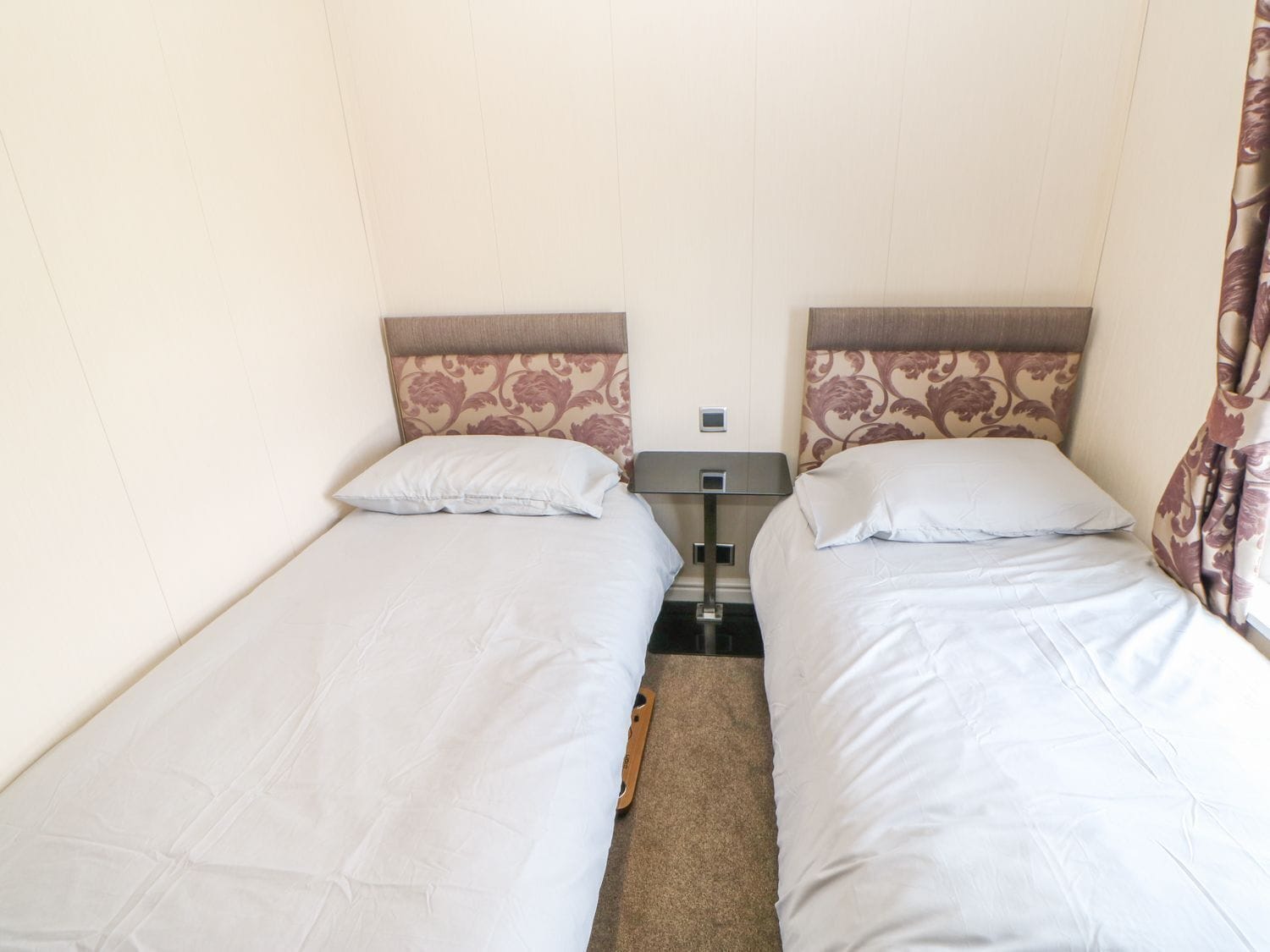 A twin room with two single beds, a nightstand, and a small table between the beds.