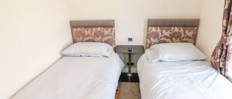 A twin room with two single beds, a nightstand, and a small table between the beds.