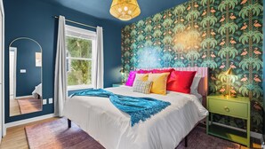 A bedroom with a large bed, a nightstand, a mirror, and a window with curtains. - A Boho City Escape  Sleeps 8 Tampa Heights (Tampa)