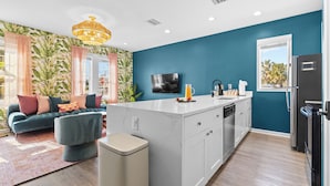 A modern kitchen with a central island, a built-in dishwasher, and a black refrigerator. - A Boho City Escape  Sleeps 8 Tampa Heights (Tampa)