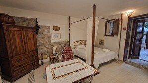 Ein Schlafzimmer mit einem Himmelbett, einem Holzschrank, einem kleinen Tisch und einem Fliesenboden.