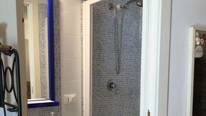 Ein Badezimmer mit Dusche, Waschbecken und Spiegel.