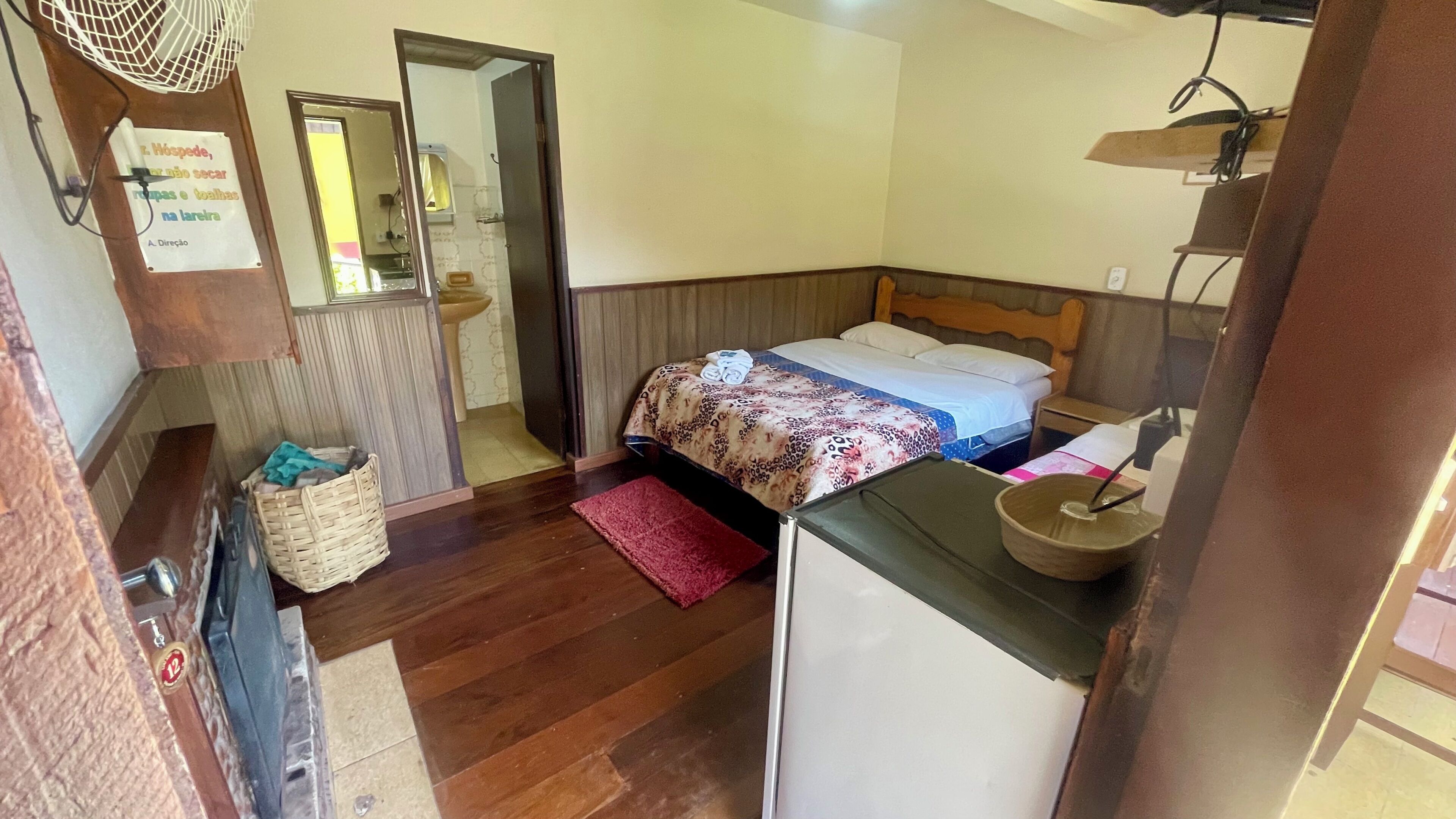 A bedroom with a bed, a small table, a sink, and a mirror.