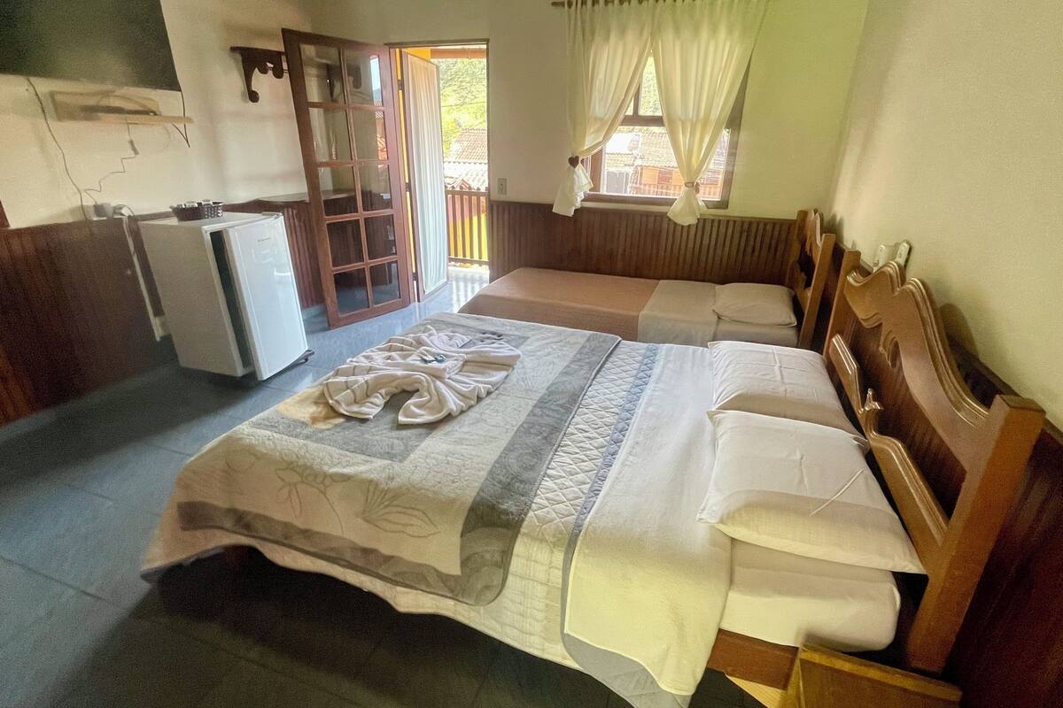 Habitación de hotel con cama, una kitchenette pequeña, una puerta que da al exterior y una ventana con cortinas.