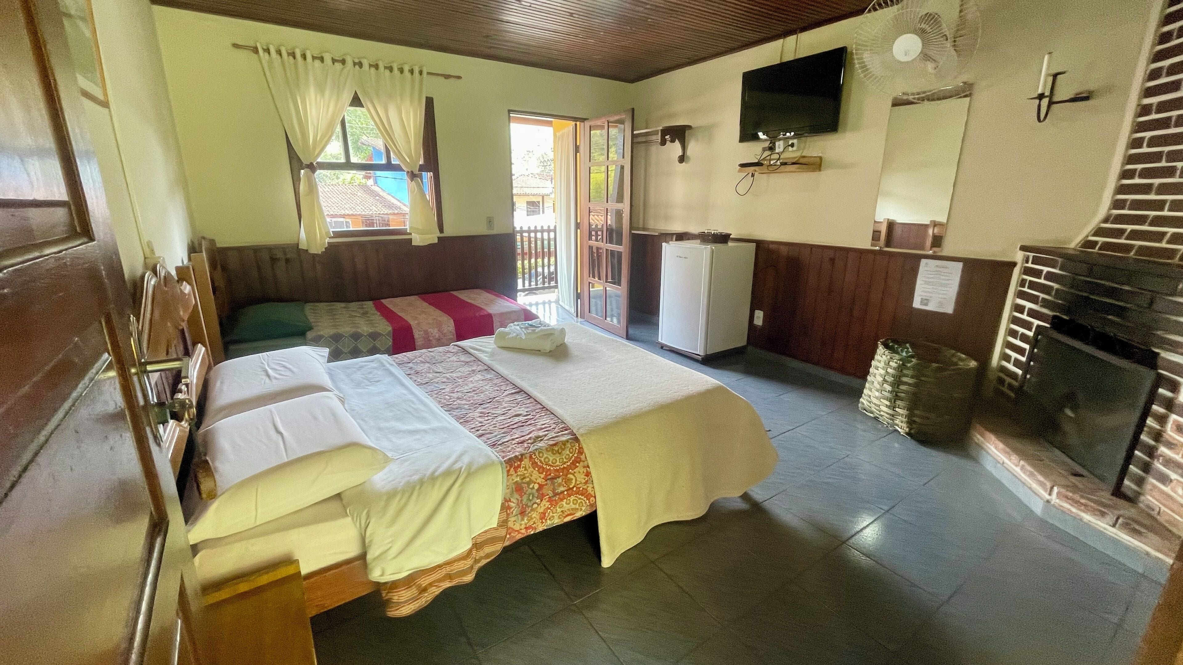 A hotel room with a bed, a television, a fireplace, and a small refrigerator.