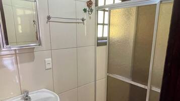 A bathroom with a sink, toilet, shower, and a mirror.