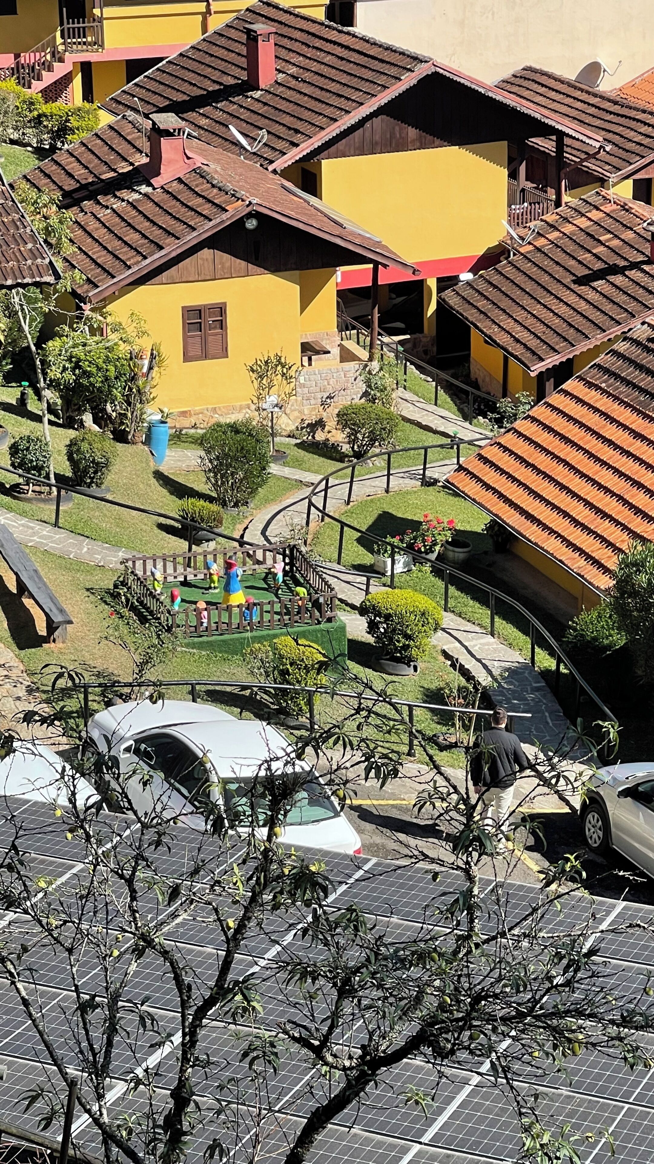 Um bairro residencial com edifícios amarelos, um parquinho e carros estacionados.