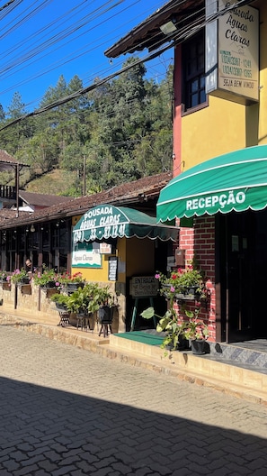 Un edificio con toldo verde que dice 'RECEPCAO' y un cartel para 'Pousada Águas Claras' con números de contacto.