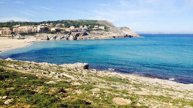 A coastal town with buildings on a hillside, a beach, and the sea.