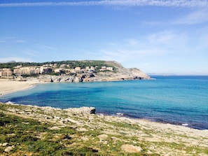 Un pueblo costero con edificios en una colina, una playa y el mar.