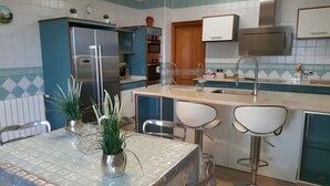 A kitchen with a refrigerator, oven, sink, and two bar stools.