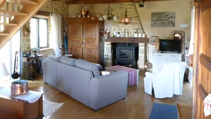 Ein gemütliches Wohnzimmer mit einer Couch, einem Kamin, einem Fernseher und einer Treppe.