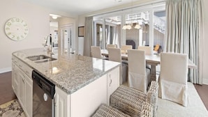 A modern kitchen with granite countertops, a dishwasher, and a dining area with wicker chairs and a table. - Bright 4BR House near Bethany Beach (Bethany Beach)