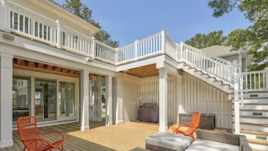 A covered outdoor patio with a wooden deck, white railings, and outdoor seating including wicker sofas and chairs. - Bright 4BR House near Bethany Beach (Bethany Beach)