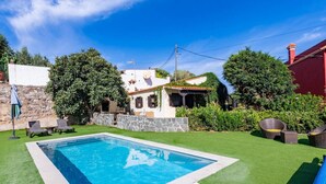 A swimming pool with a stone wall and a white building in the background.