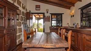 A rustic dining area with a wooden table and chairs, stone walls, and wooden cabinetry.