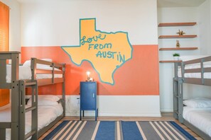 Ein Zimmer mit Etagenbetten, Wandgemälde von Texas, einem kleinen blauen Schrank und einem Streifen Teppich.