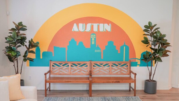 A room with a wooden bench, a white sofa, a cityscape mural, and two potted plants. - 5 STAR BIG Group FUN ~BACH / Family Trip (Austin)