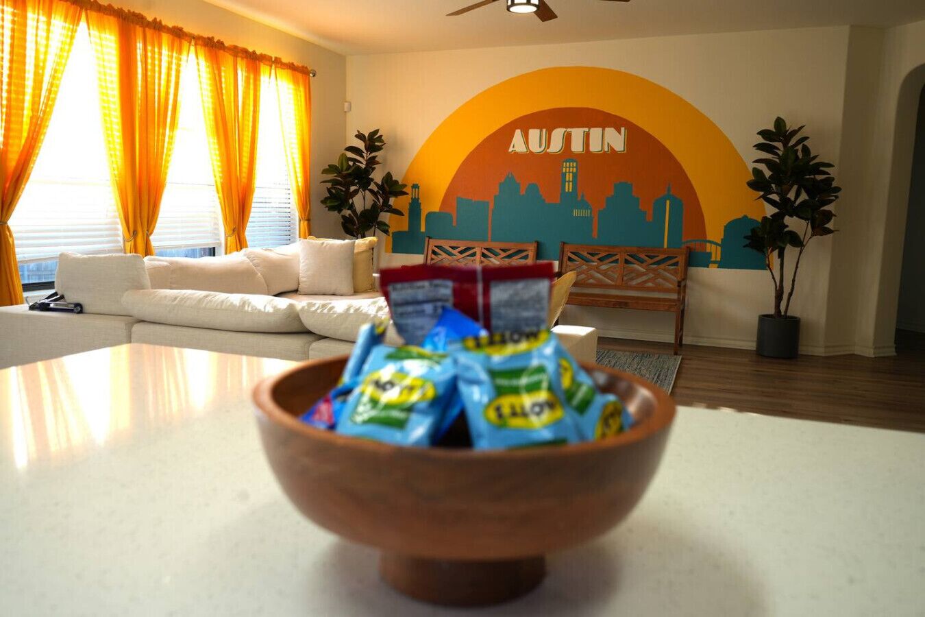 A living room with a sofa, a coffee table with snacks, and a wall mural with the word "AUSTIN".