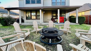 A two-story house with a covered patio area featuring a circular fire pit and several Adirondack chairs. - 5 STAR FUN ~ 14 Person Family Friendly ~BACH TRIP (Austin)