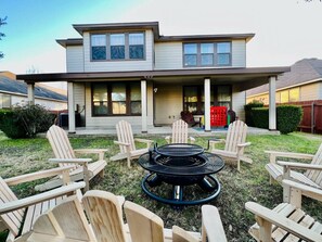 A two-story house with a covered patio area featuring a circular fire pit and several Adirondack chairs. - 5 STAR FUN ~ 14 Person Family Friendly ~BACH TRIP (Austin)