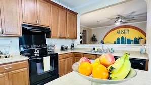 A kitchen with wooden cabinets, a black stove, and a fruit bowl on the counter. - 5 STAR FUN ~ 14 Person Family Friendly ~BACH TRIP (Austin)