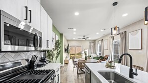 Una cucina moderna con elettrodomestici in acciaio inossidabile, una zona pranzo con tavolo rotondo e vista sul giardino.