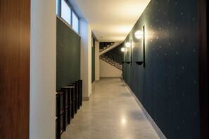 A hallway with a staircase, wooden paneling, and wall-mounted lighting fixtures. - Garibaldi 23 Central Apart Trilo by BarbarHouse (Bari)