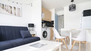 Ein modernes Wohnzimmer mit einem dunkelblauen Sofa, einem weißen Couchtisch und einem Essbereich mit weißen Stühlen und einem weißen Tisch.