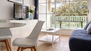 Ein modernes Wohnzimmer mit Balkon, Essbereich und Fernseher.