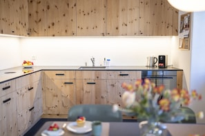 Eine moderne Küche mit Holzausstattung, einer Edelstahlspüle und einer Kaffeemaschine.